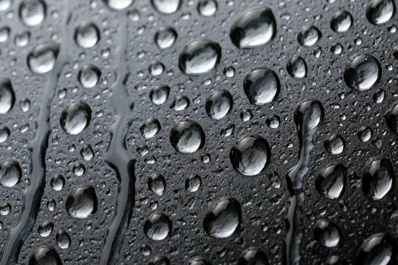Water droplets scattered across dark wet glass surface