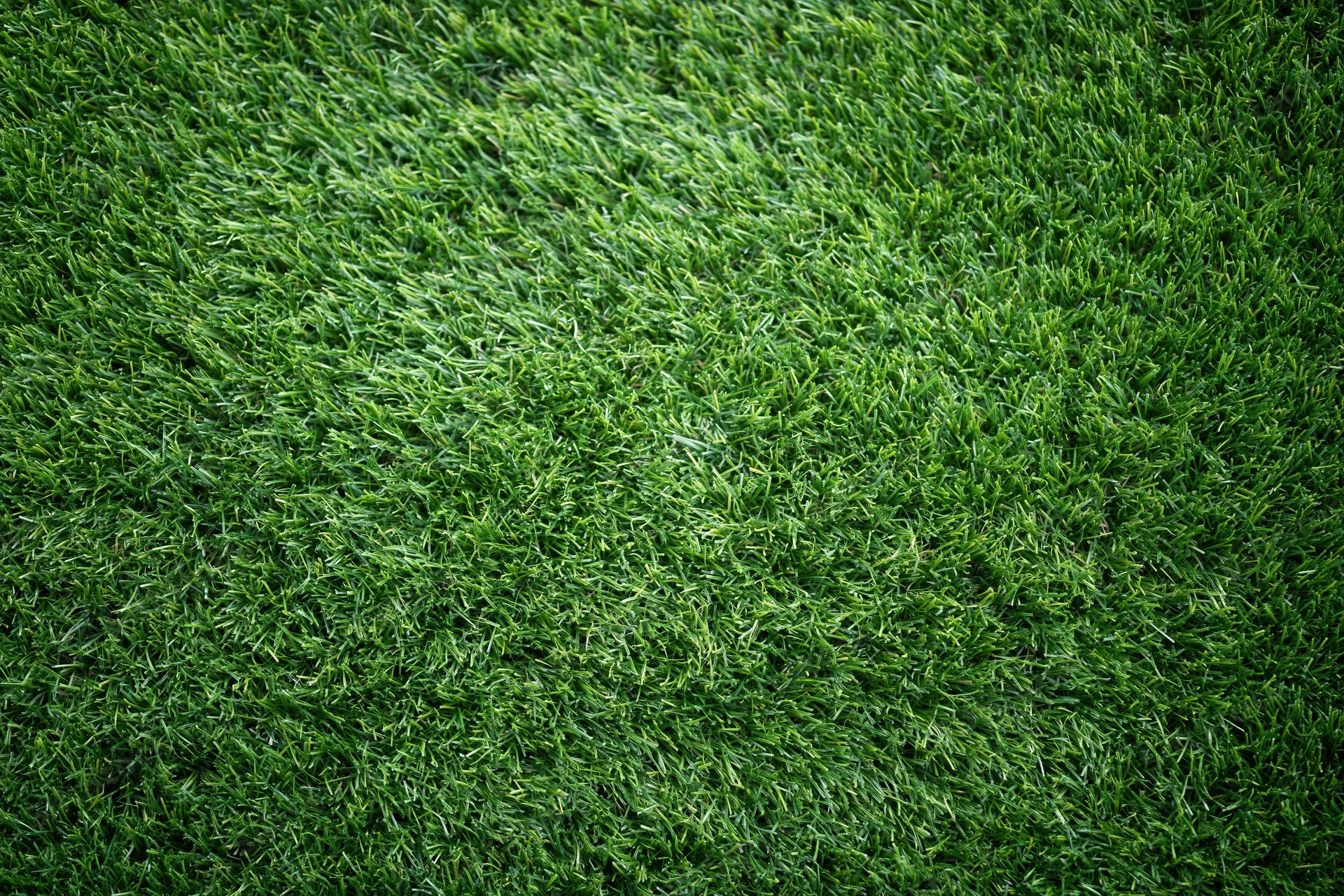 Artificial turf surface viewed from overhead in close-up, filling the frame with green synthetic grass texture