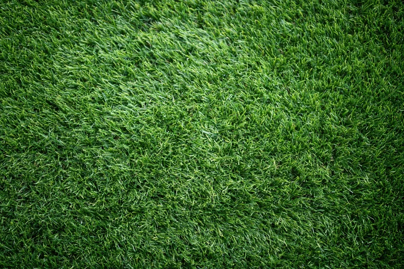 Artificial turf surface viewed from overhead in close-up, filling the frame with green synthetic grass texture