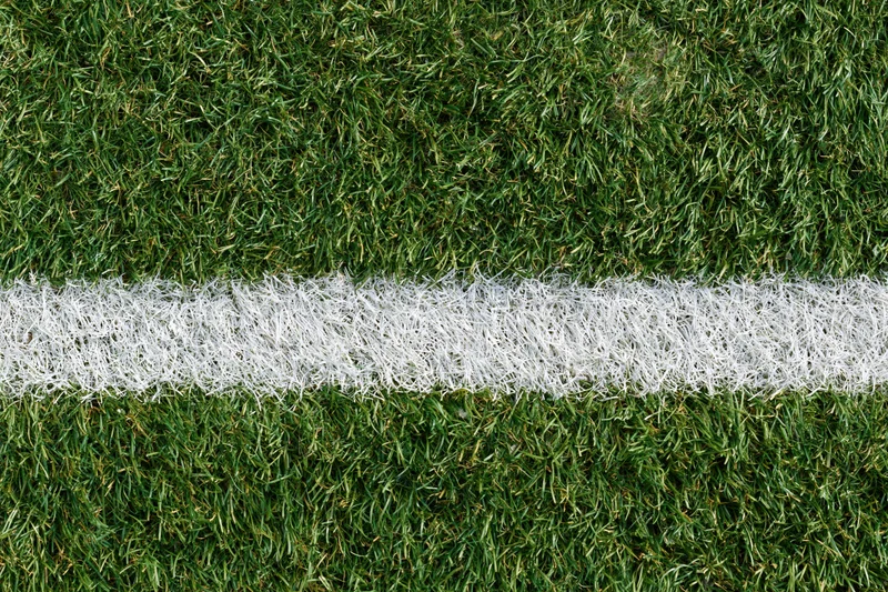 Close-up overhead view of artificial turf with white boundary line on sports field