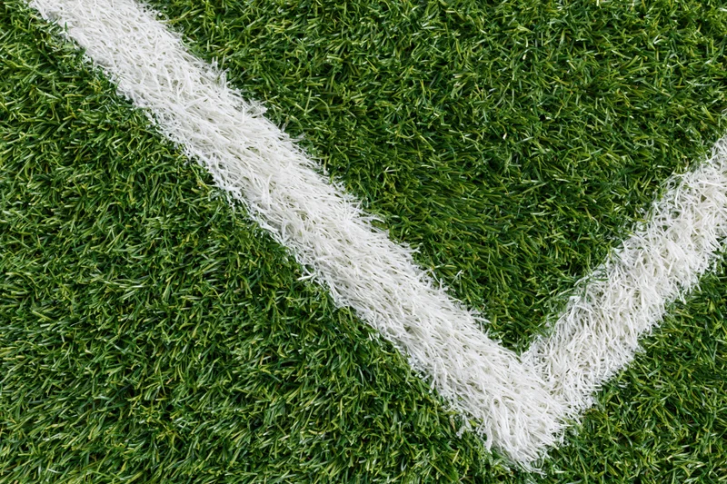 Close-up overhead view of artificial turf soccer field corner with white boundary lines