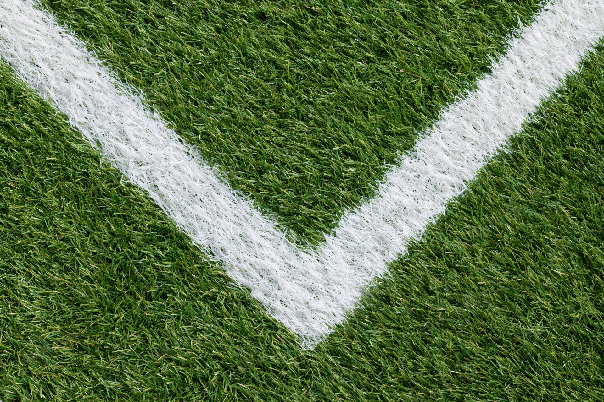 Close-up overhead view of artificial turf soccer field corner with white boundary lines