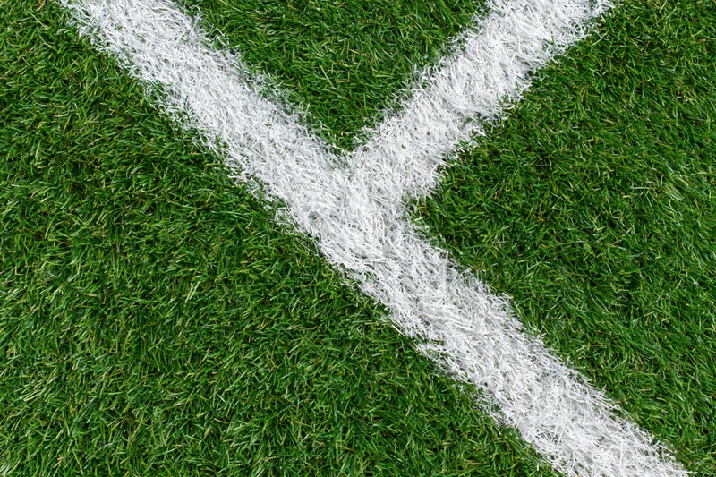 Artificial turf soccer field corner with white intersecting lines overhead view