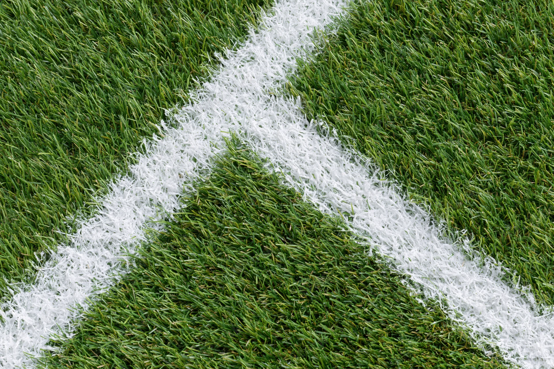 Close-up overhead view of artificial turf soccer field corner with white boundary line