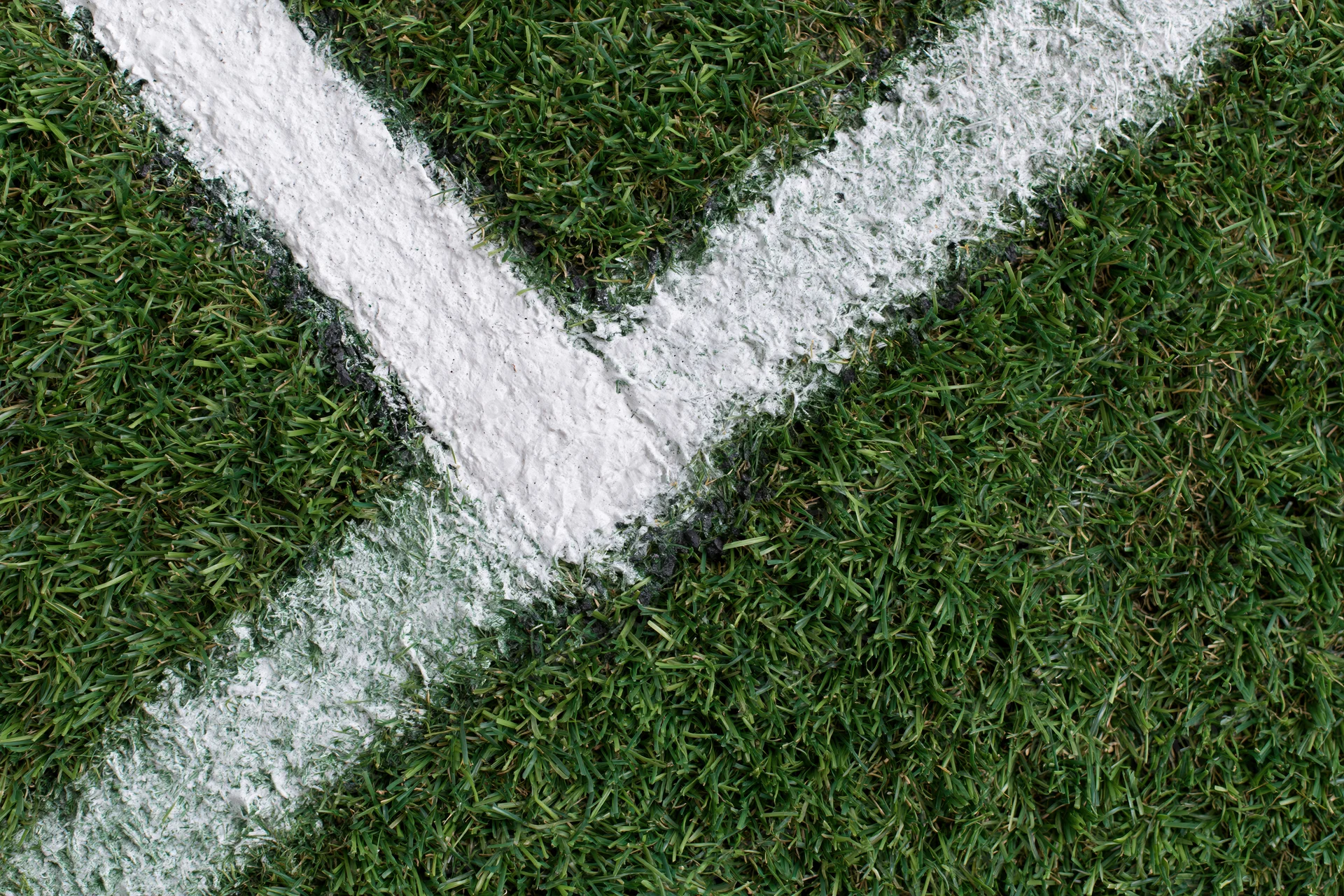 White corner marking lines on a green soccer field grass surface viewed from above
