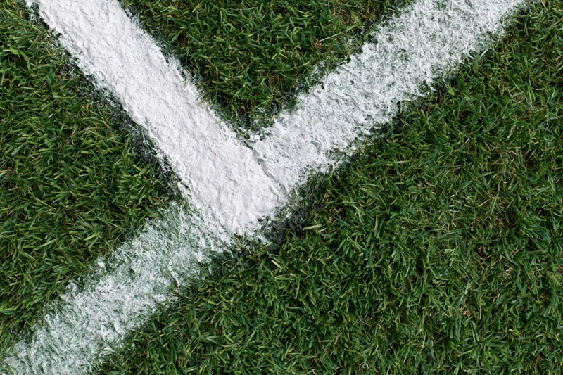 White corner marking lines on a green soccer field grass surface viewed from above