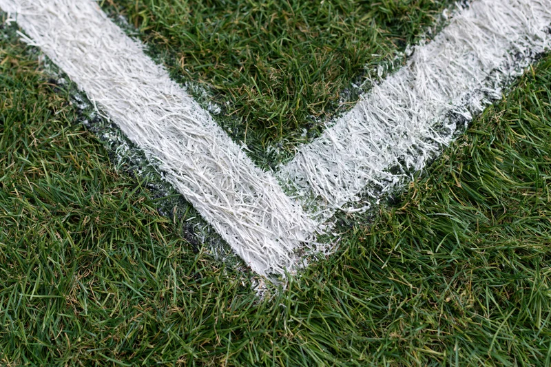Close-up top-down view of white corner marking lines on a green grass soccer field