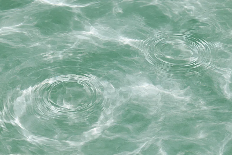 Still water surface with two circular ripples creating concentric patterns