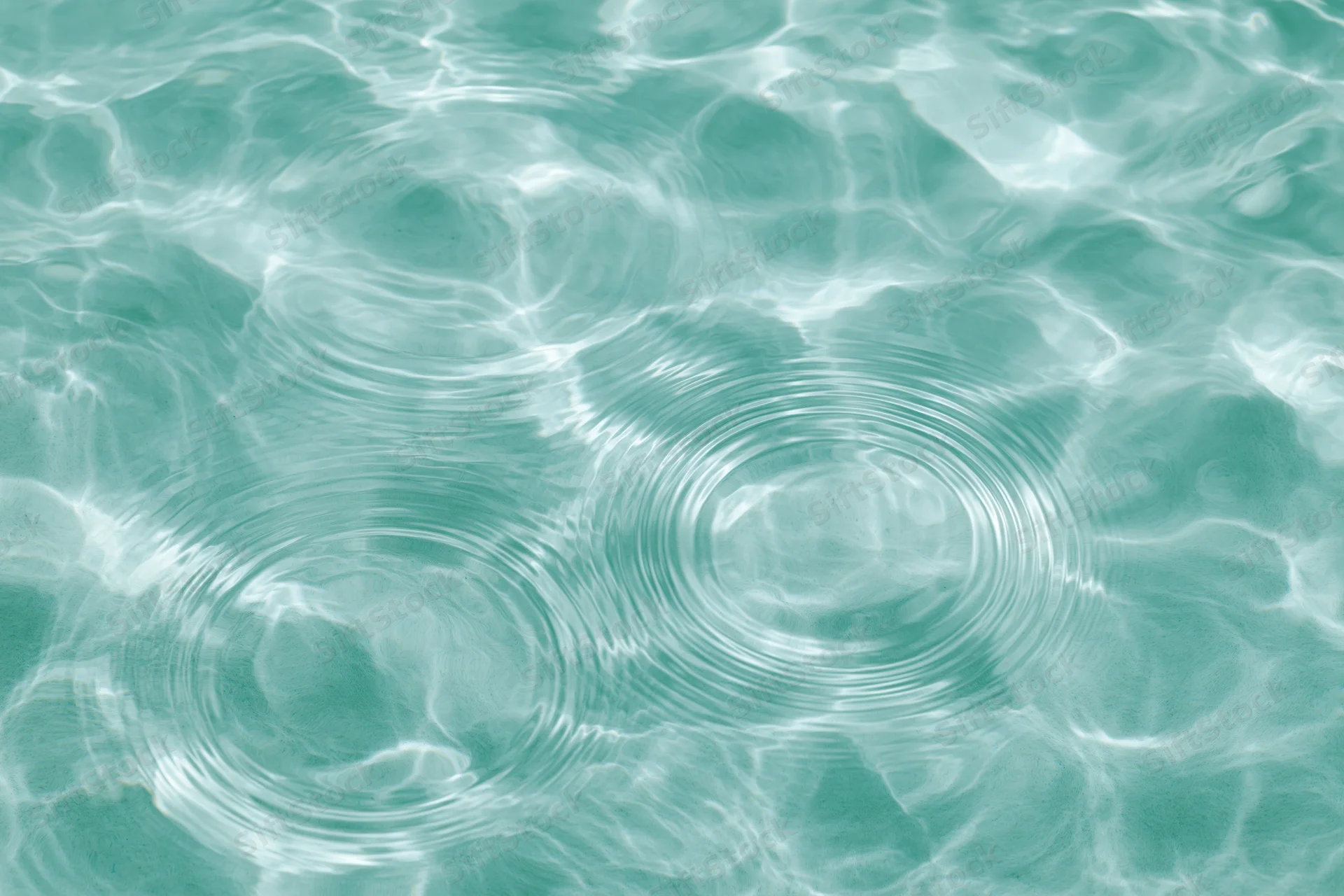 Still water surface with two sets of concentric ripples creating a pattern of light and shadow