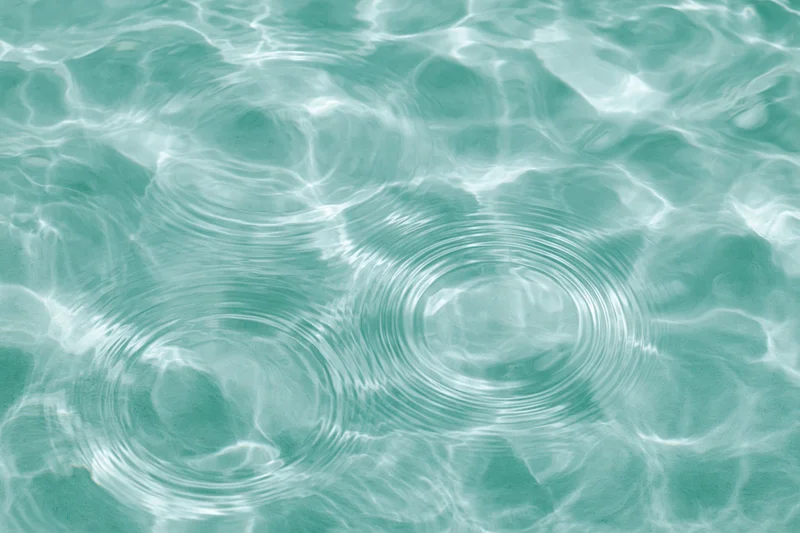 Still water surface with two sets of concentric ripples creating a pattern of light and shadow