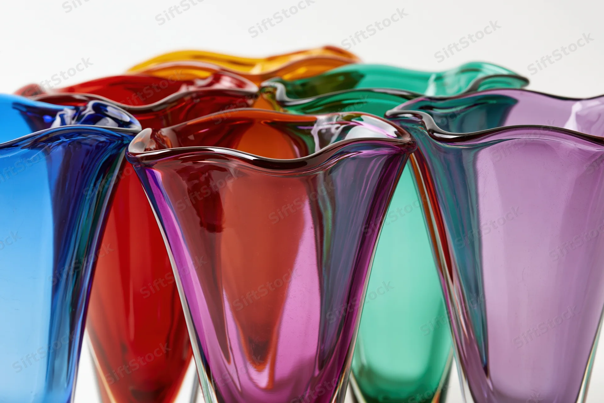 Collection of midcentury murano art glass vases with flared rims arranged in a row on a white background