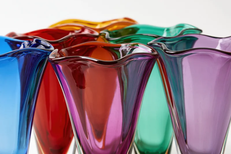 Collection of midcentury murano art glass vases with flared rims arranged in a row on a white background