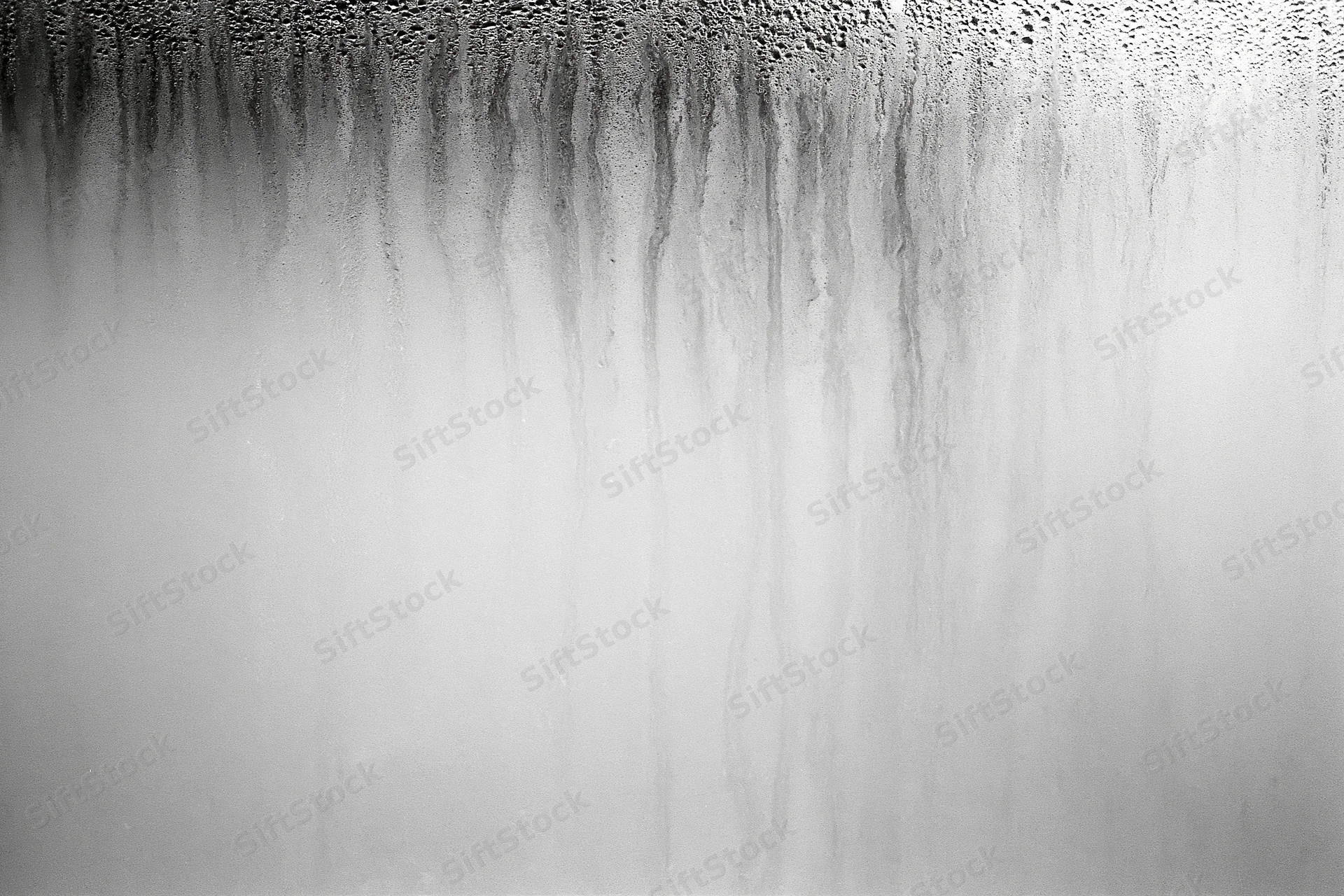 Condensation and water streaks running down a fogged glass surface