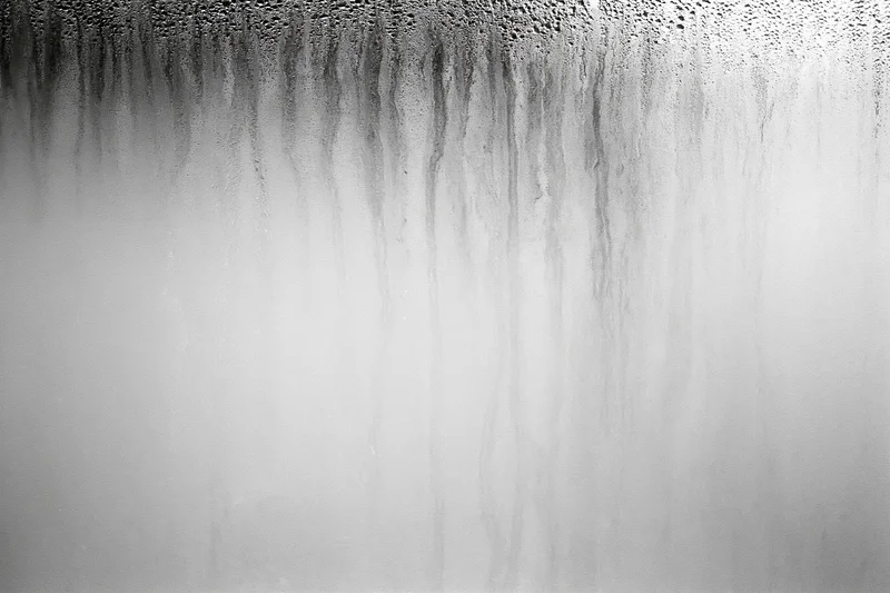 Condensation and water streaks running down a fogged glass surface