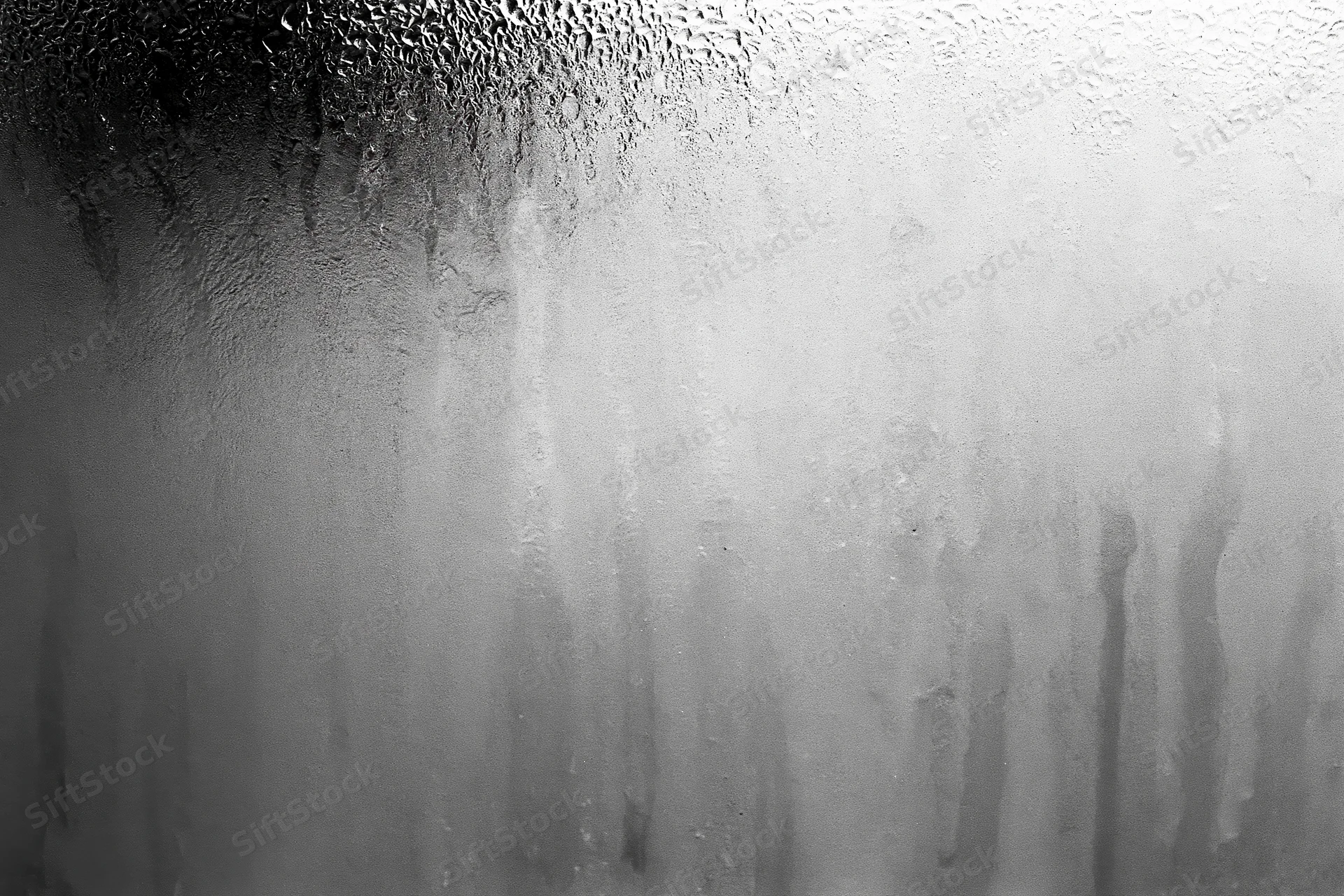 Condensation and water streaks running down a fogged glass surface