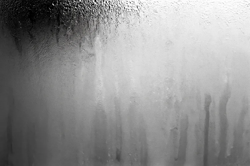Condensation and water streaks running down a fogged glass surface