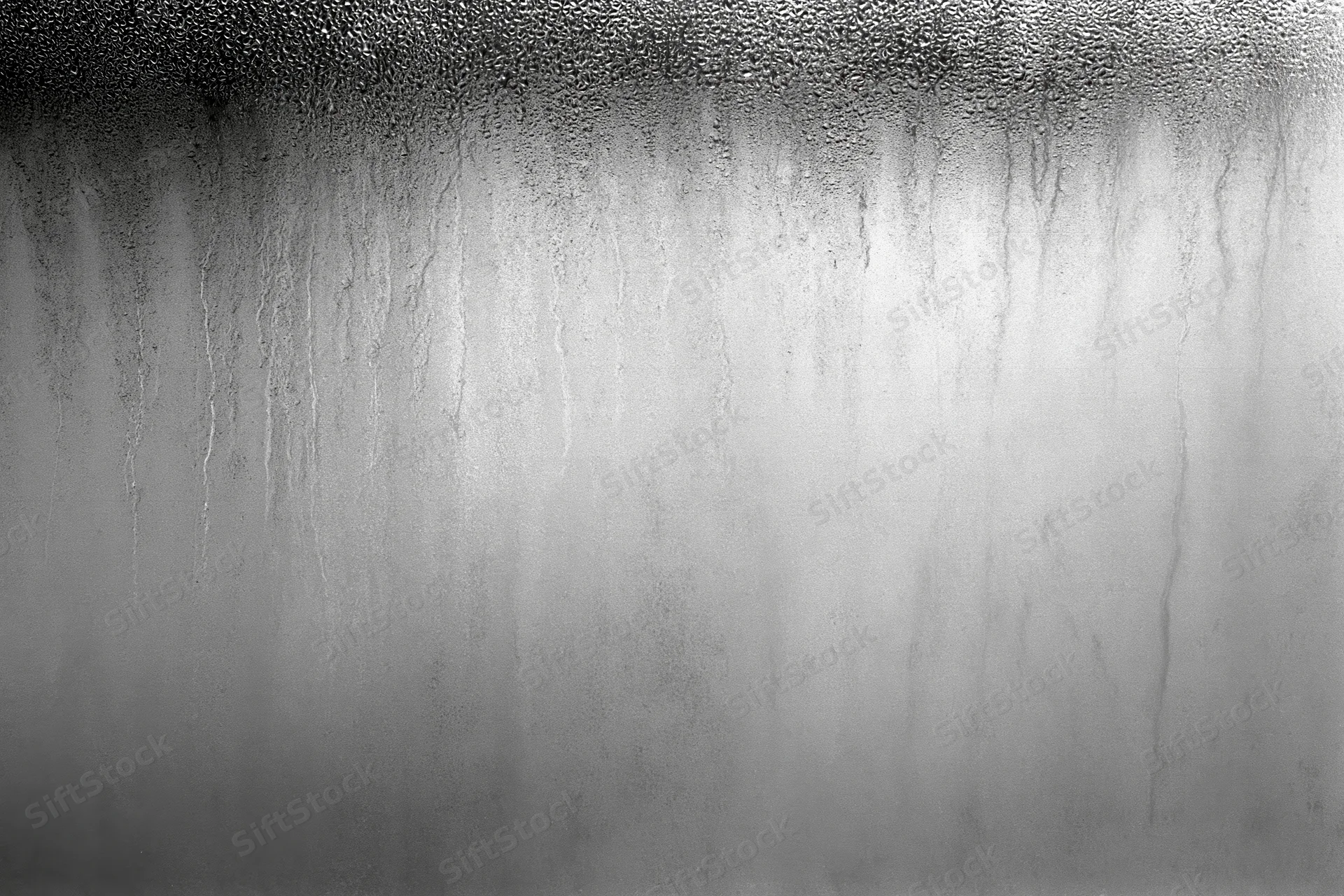 Condensation and water streaks running down a fogged glass surface
