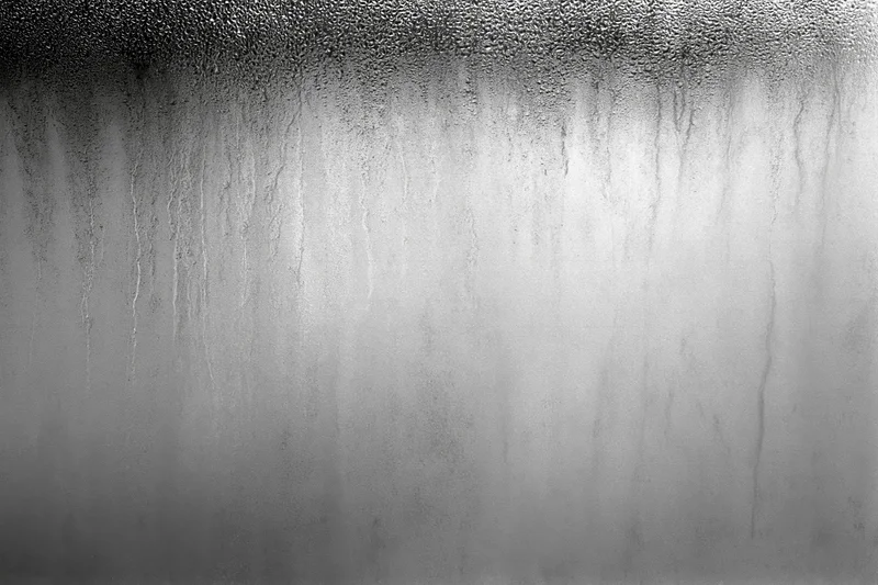 Condensation and water streaks running down a fogged glass surface