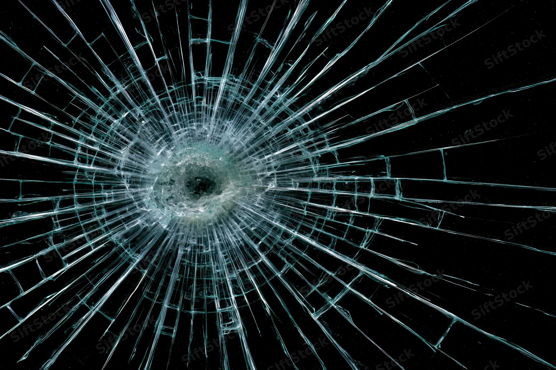 Cracked glass panel with radial fractures radiating from central impact point against black background