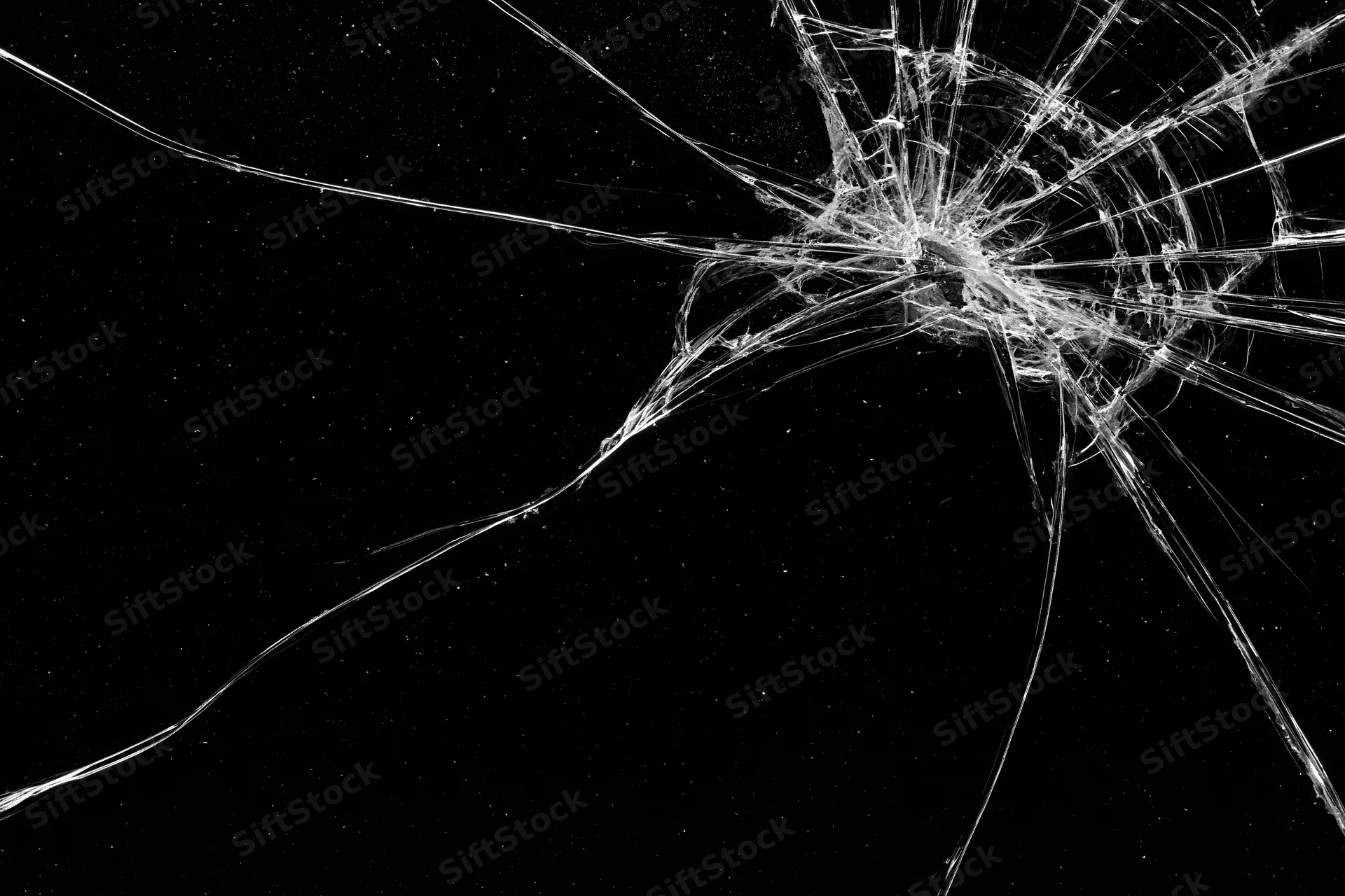Cracked glass surface with radiating fracture lines spreading across dark background