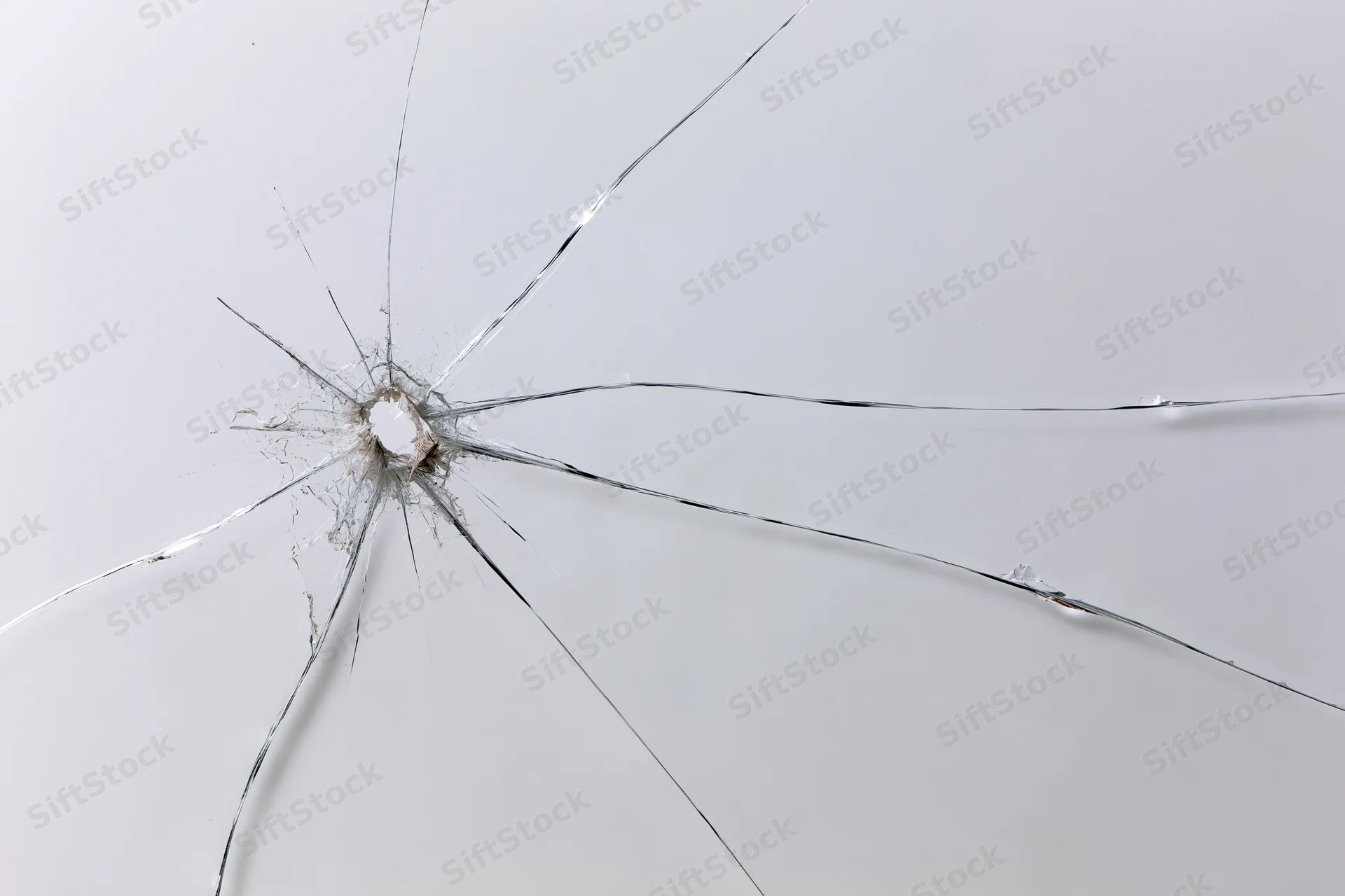 Cracked glass surface with radial fracture lines spreading from central impact hole