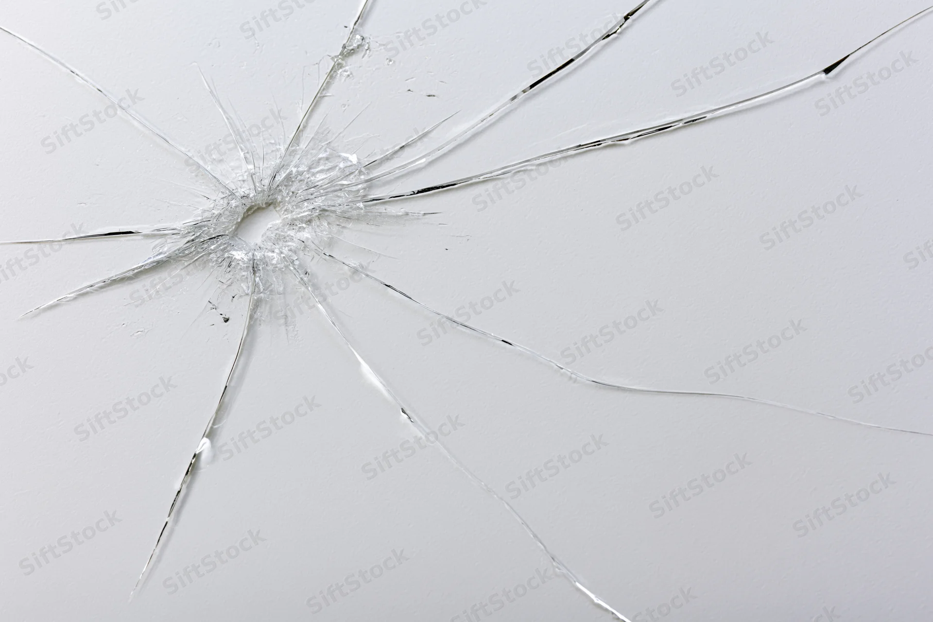 Cracked glass surface with thin radiating fracture lines spreading from central impact point