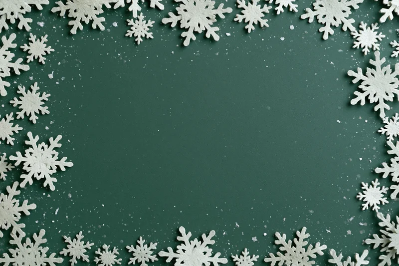 White snowflake decorations arranged in a border around a green background with copyspace in center