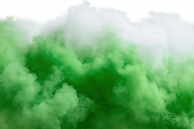 Dense green smoke cloud dissipating against a plain white background