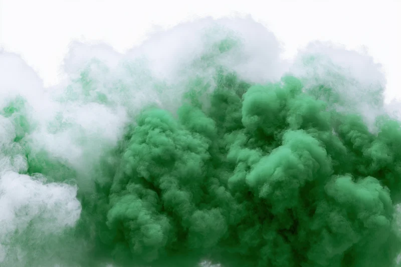 Dense green smoke cloud dissipating against plain white background