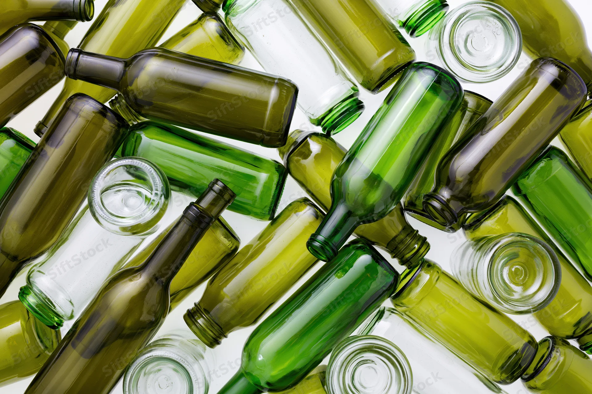Empty green and clear glass wine bottles scattered on white surface