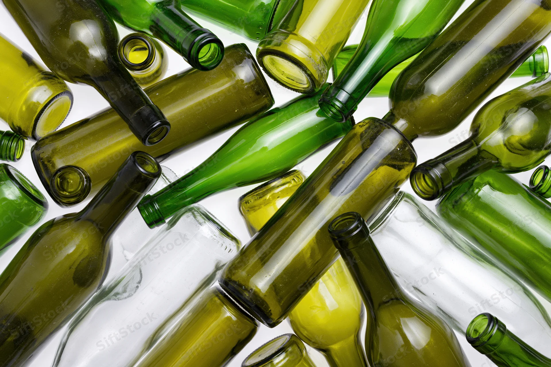 Empty green and clear glass wine bottles scattered on white surface