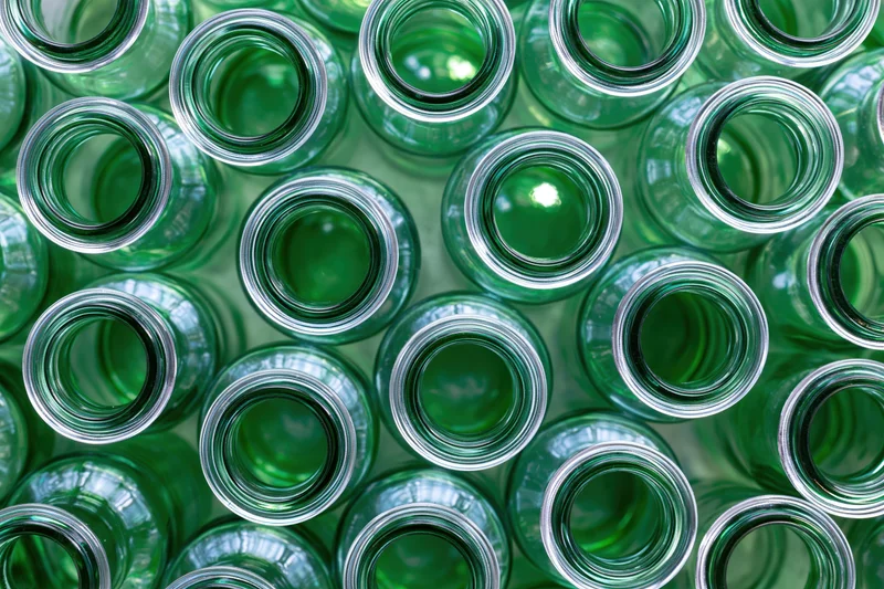 Empty green glass bottles packed tightly together in overhead view