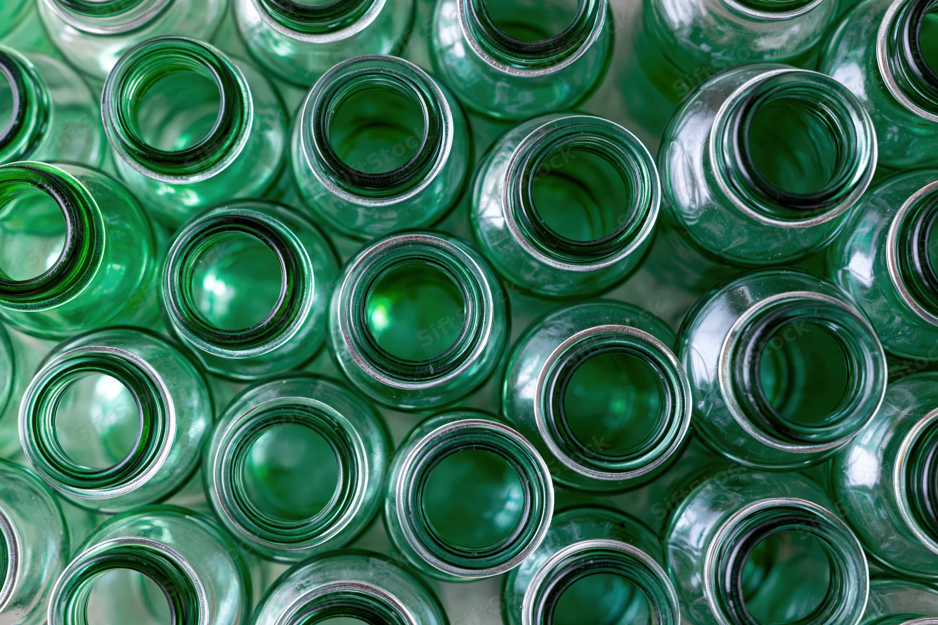 Empty green glass bottles packed tightly together in overhead view