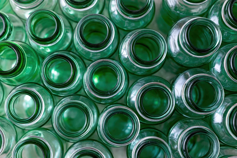 Empty green glass bottles packed tightly together in overhead view