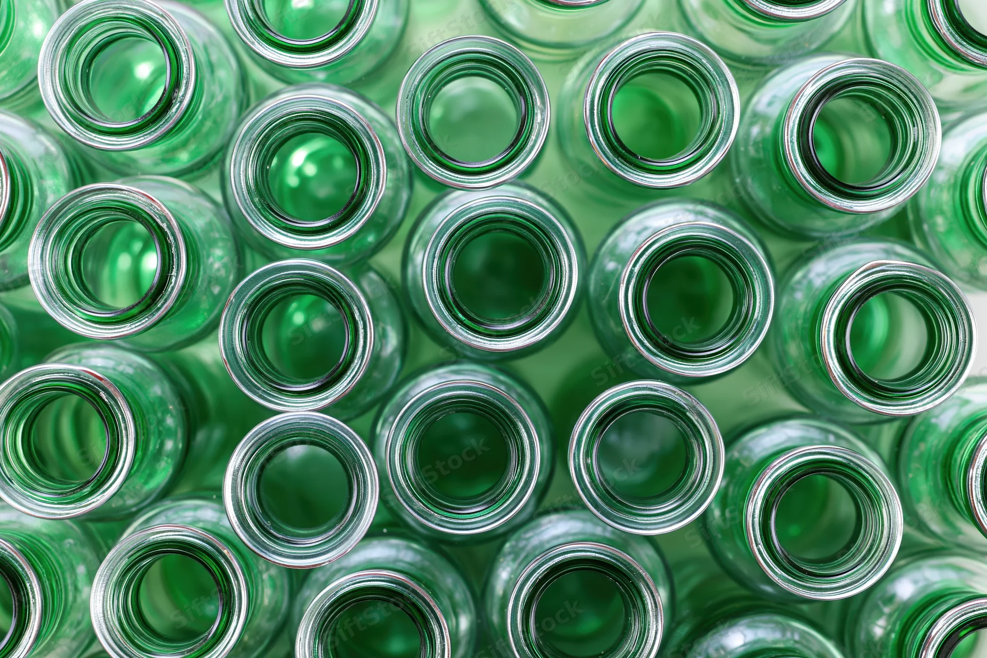 Empty green glass bottles packed tightly together in overhead view