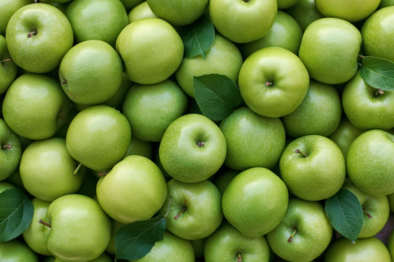 Dozens of fresh green granny smith apples piled together filling the frame