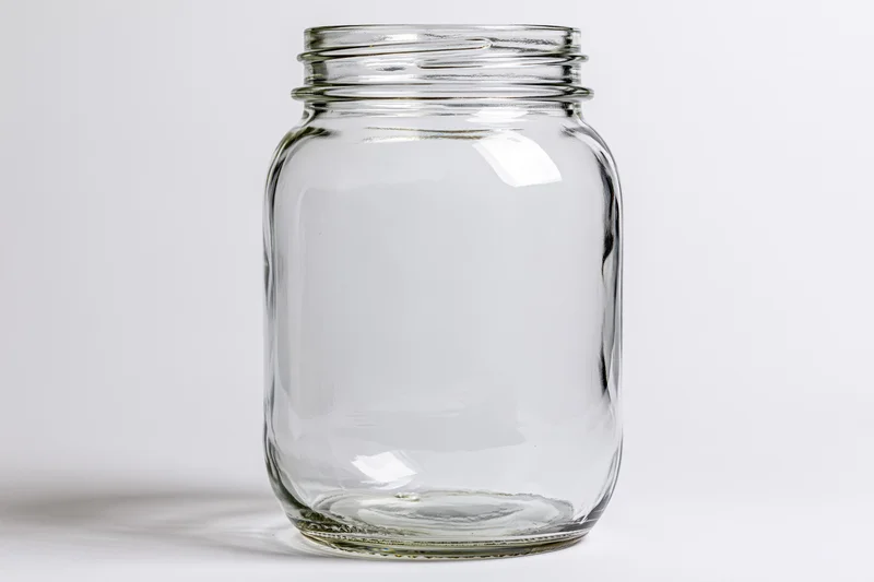 Empty clear glass mason jar with no lid shot straight-on against white background