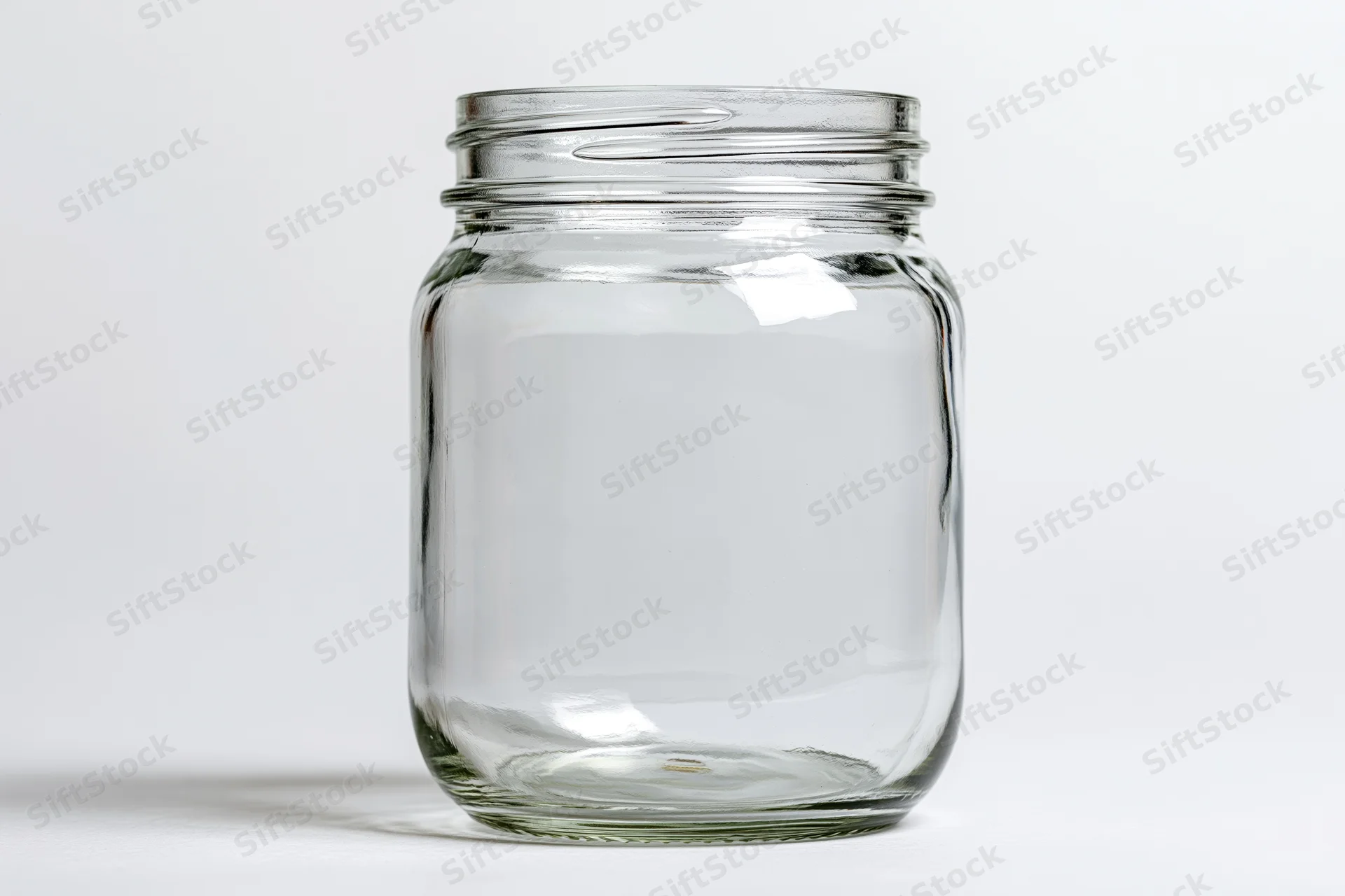 Empty clear glass mason jar with no lid shot straight-on against white background