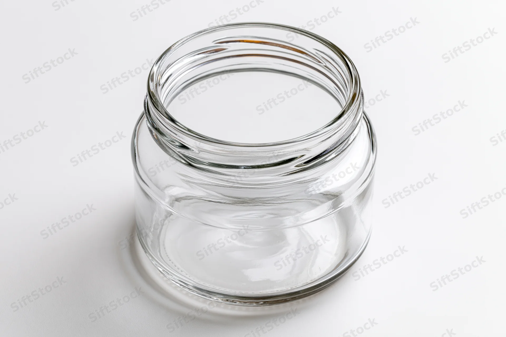 Empty clear glass mason jar with no lid shot straight-on against white background