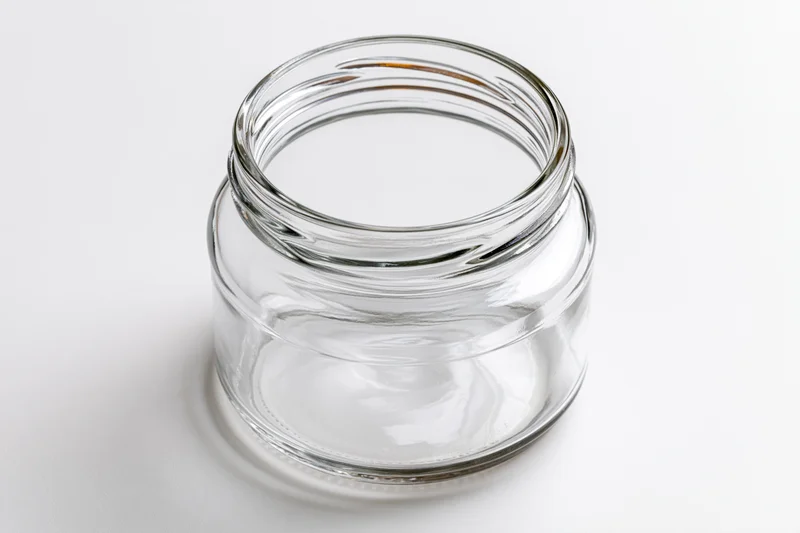 Empty clear glass mason jar with no lid shot straight-on against white background