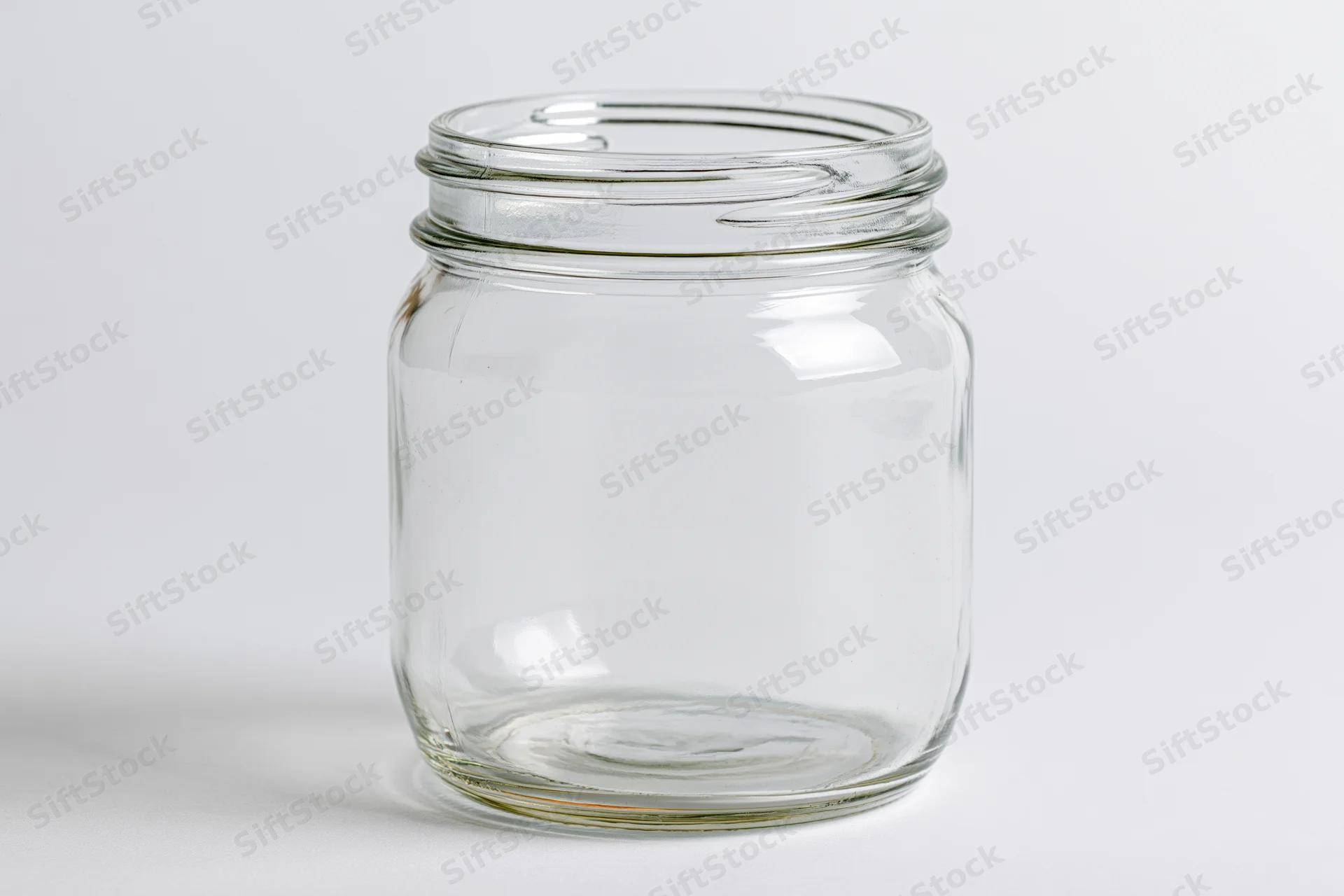 Empty clear glass mason jar with no lid shot straight-on against white background