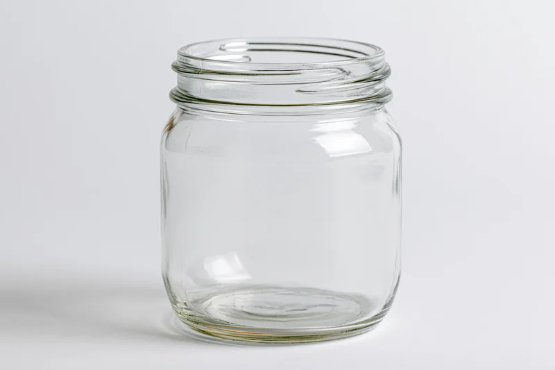 Empty clear glass mason jar with no lid shot straight-on against white background
