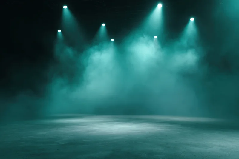 Empty stage floor illuminated by teal spotlights with smoke in theater setting