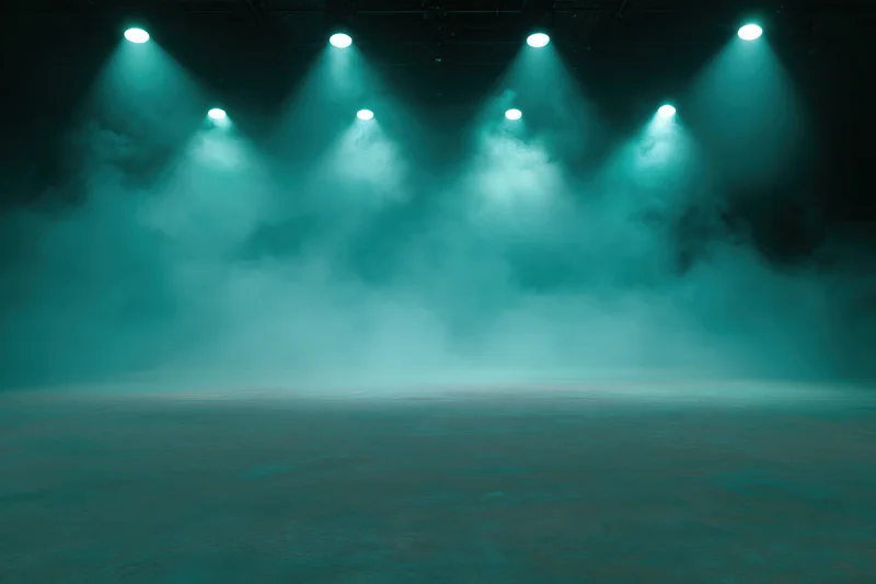 Empty stage floor illuminated by teal spotlights with smoke under dark ceiling