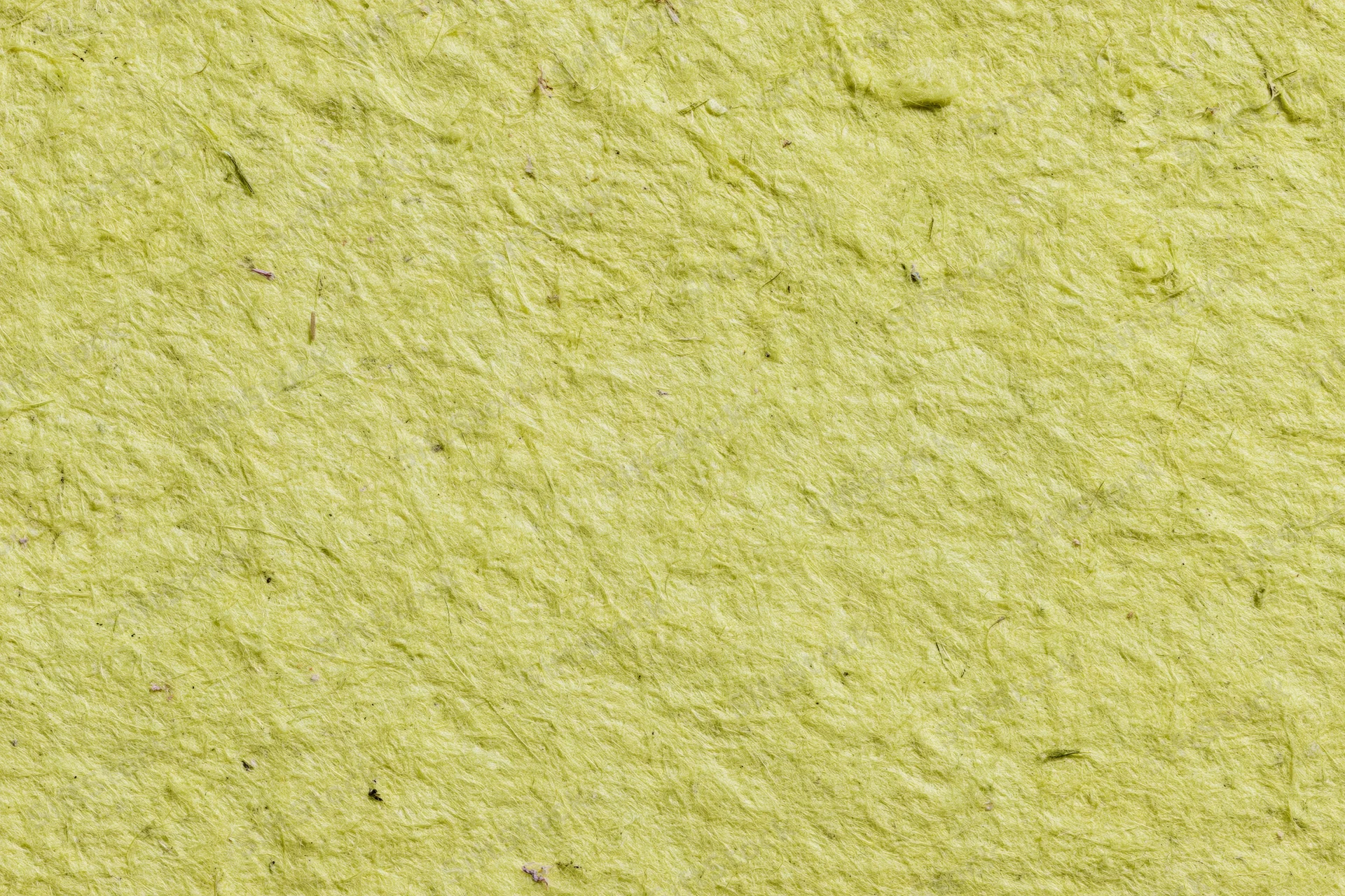 Close-up of a sheet of handmade recycled paper with visible fibers and textured surface