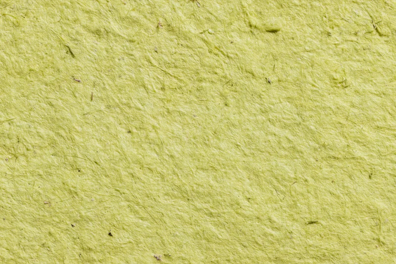 Close-up of a sheet of handmade recycled paper with visible fibers and textured surface