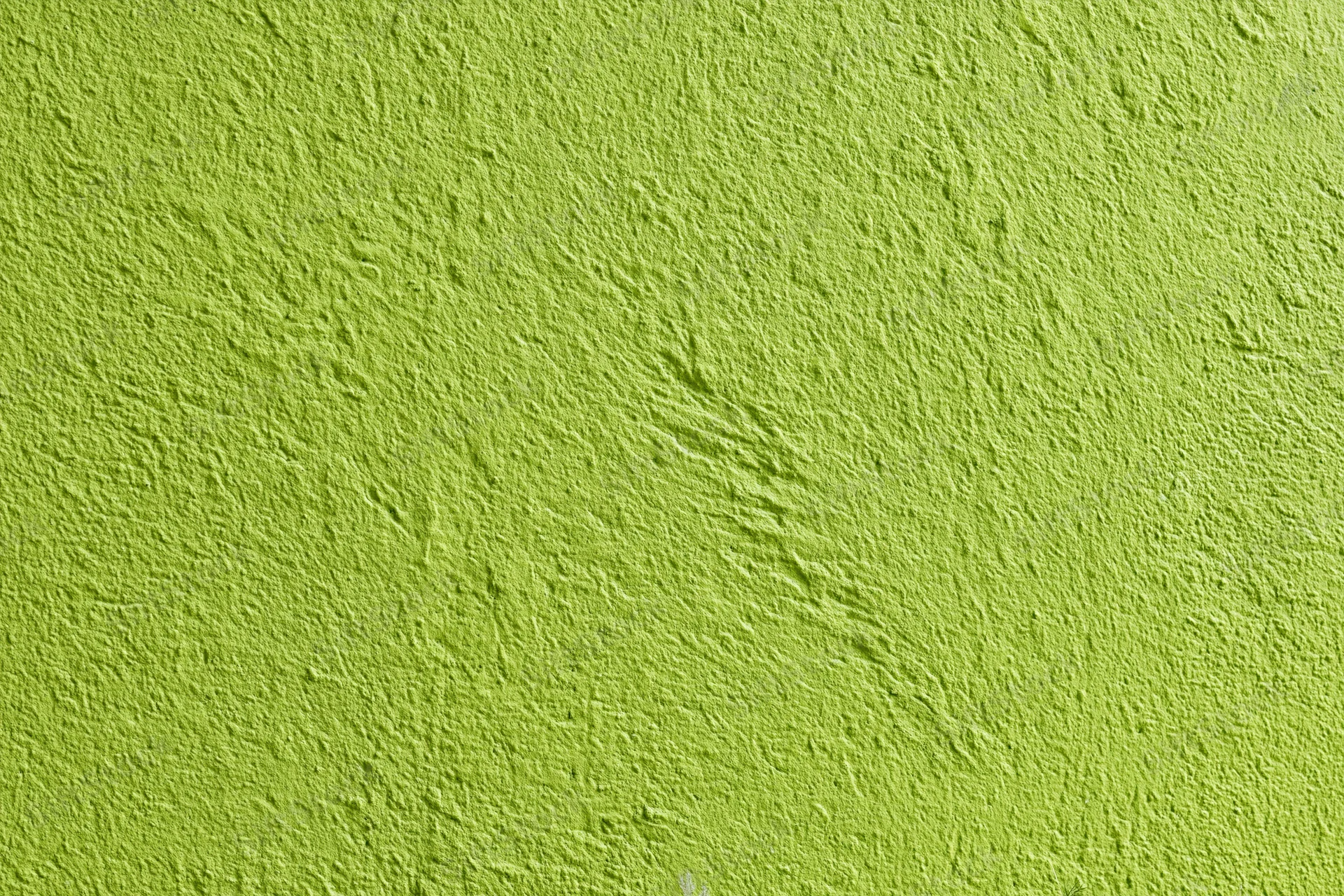 Bright grass green textured stucco wall filling the frame as a background surface
