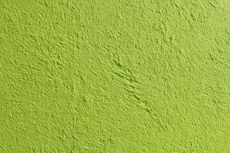 Bright grass green textured stucco wall filling the frame as a background surface