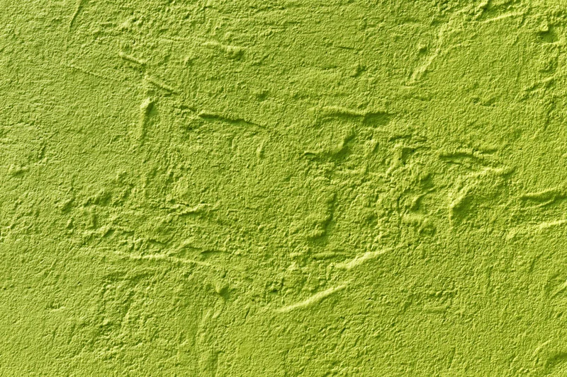 Textured stucco wall painted bright grass green filling the frame