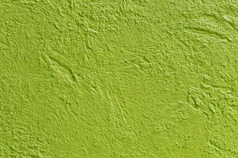 Textured stucco wall painted bright grass green filling the frame